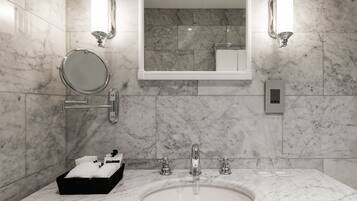 A bathroom with a marble sink, a round mirror, and two wall-mounted light fixtures.