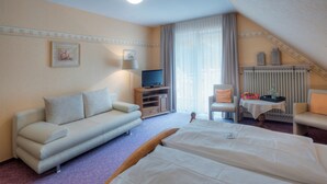 Een hotelkamer met een bank, een bed, een televisie, een stoel en een klein tafeltje met dienblad.