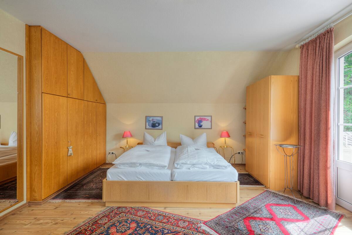 Un dormitorio con una cama grande, un armario de madera y una ventana con cortinas.