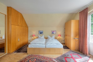 A bedroom with a large bed, wooden wardrobe, and a window with curtains. - Hotel am Schwanenweiher (Bad Bertrich)