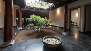 Un espace intérieur vaste, doté d’un sol carrelé, d’un grand récipient décoratif rempli d’eau et de pierres, et d’une plante en pot.