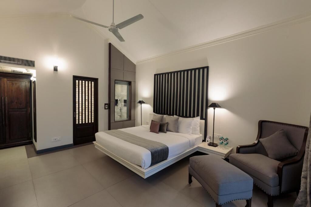 Quarto moderno com cama, mesas de cabeceira, uma cadeira, ventilador de teto e painel na parede.