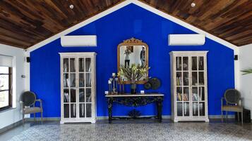 Una habitación con techos altos, dos armarios blancos con puertas de vidrio, una consola central con objetos decorativos y un espejo grande encima.