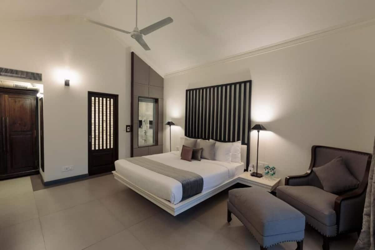 Quarto moderno com cama, mesas de cabeceira, uma cadeira, ventilador de teto e painel na parede.