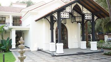 A building with a covered entrance, columns, and a stone fountain.