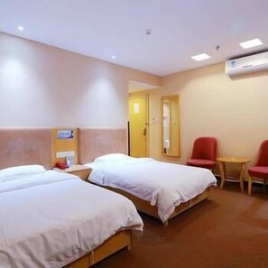 A hotel room with two beds, a small table, two red chairs, and an air conditioning unit on the wall. - Haifan Hotel (Guangzhou)