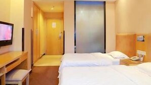 Habitación de hotel con dos camas, un escritorio y una televisión.