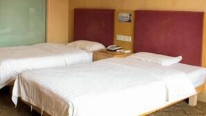 Habitación de hotel con dos camas individuales, cabecero de madera, pared verde y una mesita de noche pequeña con un teléfono.