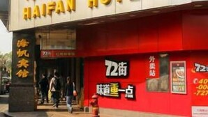 Un letrero de hotel con el nombre 'HAIFAN HOTEL' en letras amarillas grandes sobre un fondo blanco.
