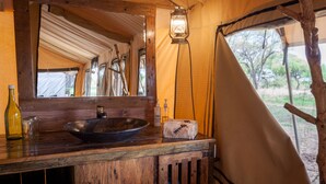 Un lavabo de madera rústica con cuenca, un espejo y un farol colgante en un alojamiento tipo tienda.
