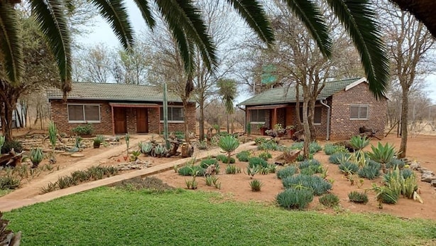 A residential area with two brick houses, a well-maintained garden with various plants, and a grassy lawn. - Zingela Nature Reserve - Doornstock Lodge (Blouberg)