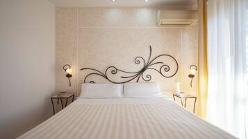 Una camera d'albergo con un letto grande, due comodini, una testiera decorativa e un condizionatore d'aria.