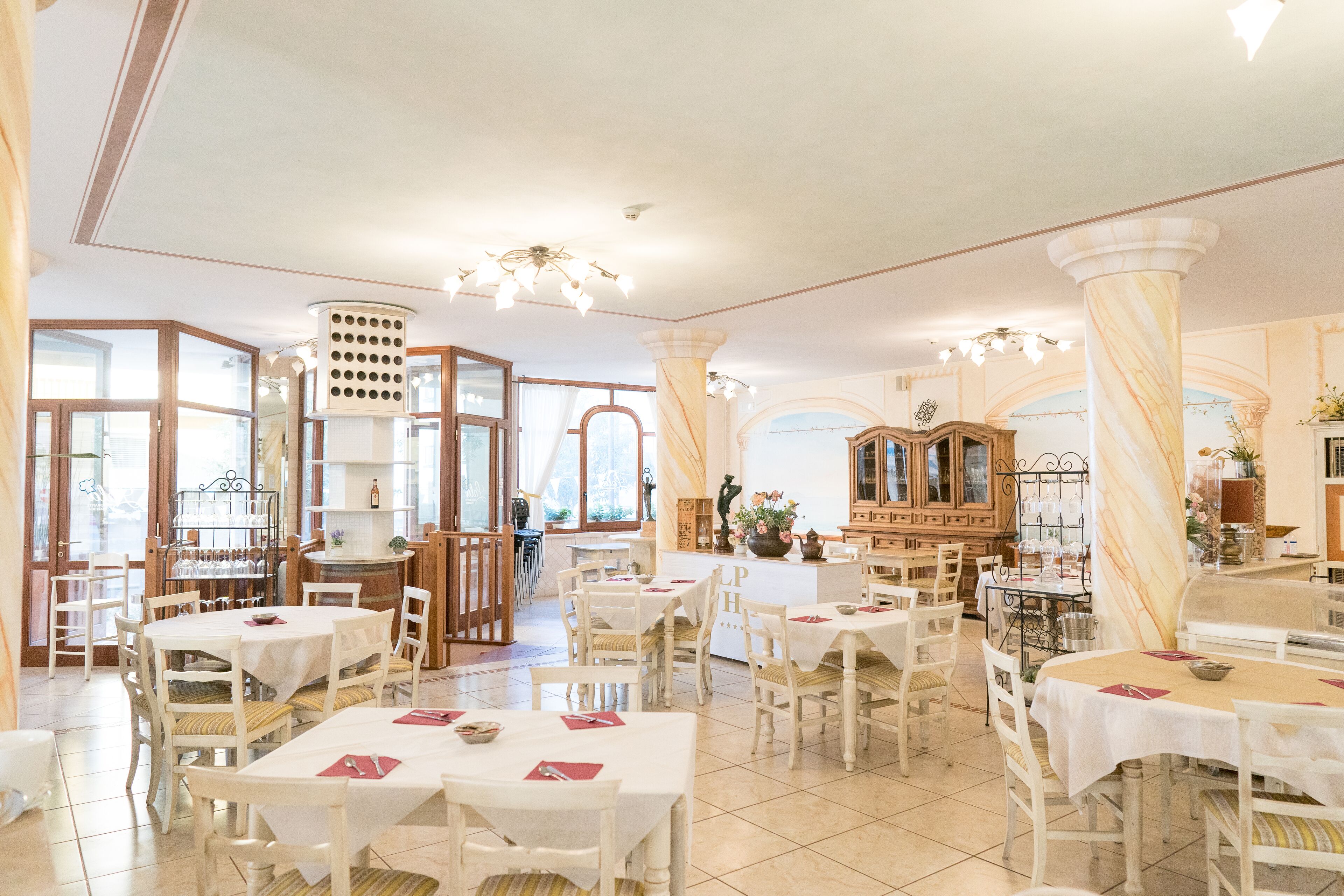 Zona de dinar espaiosa amb diverses taules i cadires, una zona de bar central i grans finestres que deixen entrar llum natural.