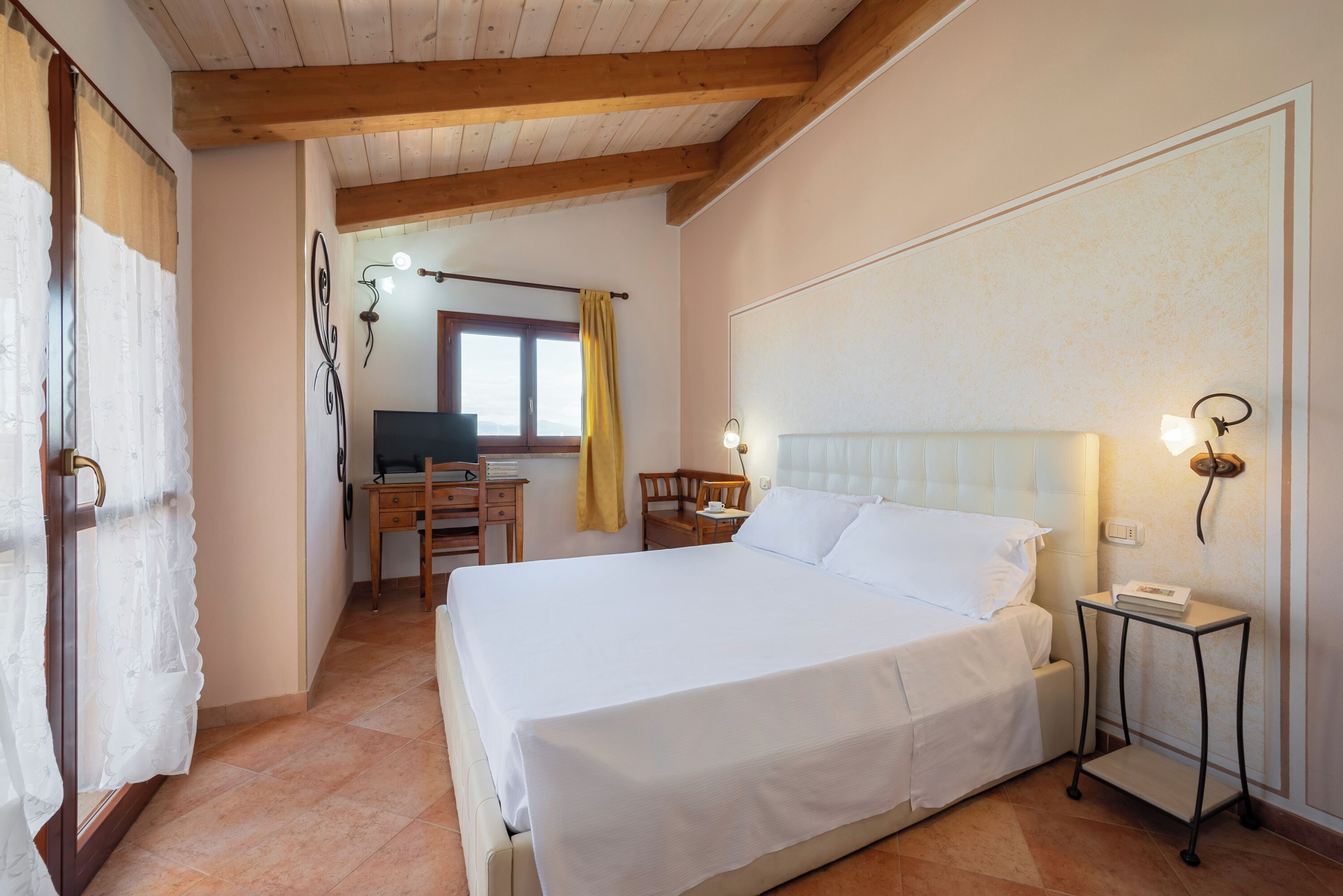 A bedroom with a large bed, a desk, and a chair.