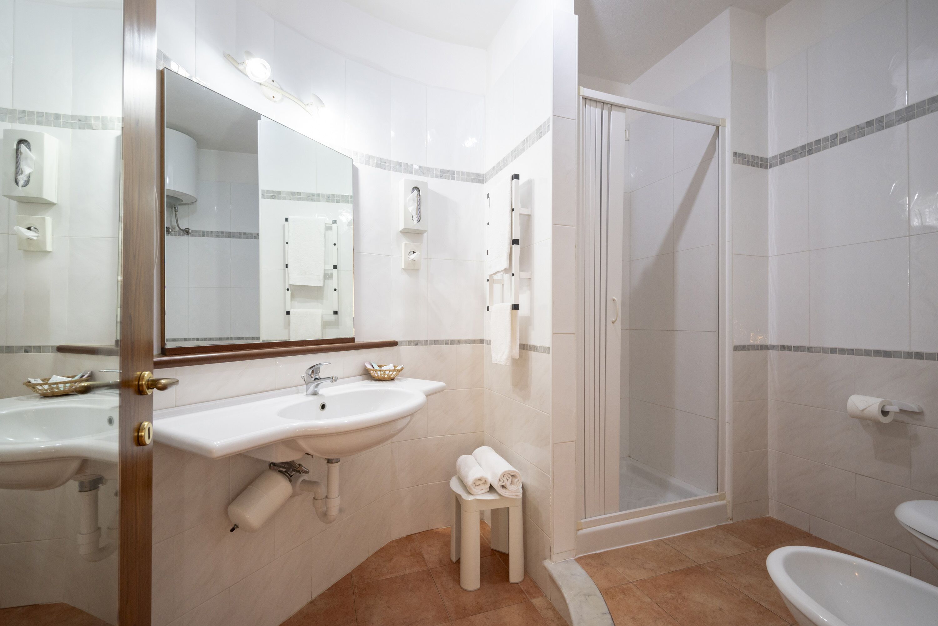 A bathroom with a sink, mirror, towel rack, shower, and toilet.