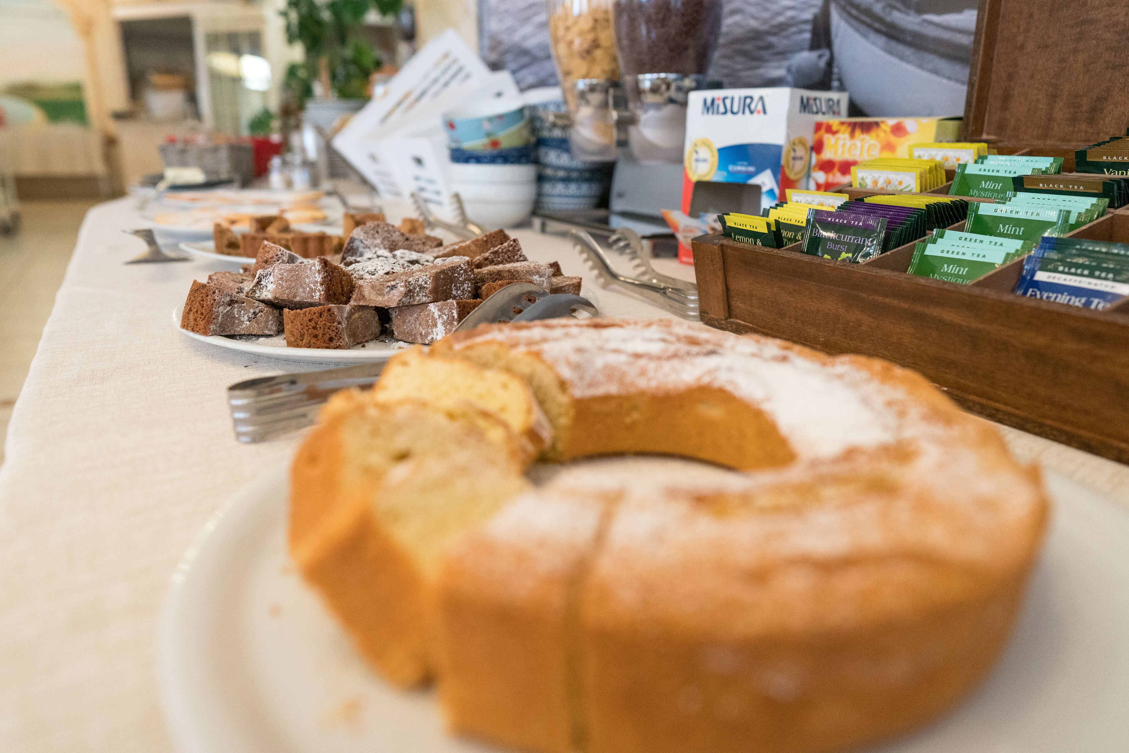 Una mesa de buffet con diversos alimentos, incluyendo un pastel grande y varias fuentes de brownies.