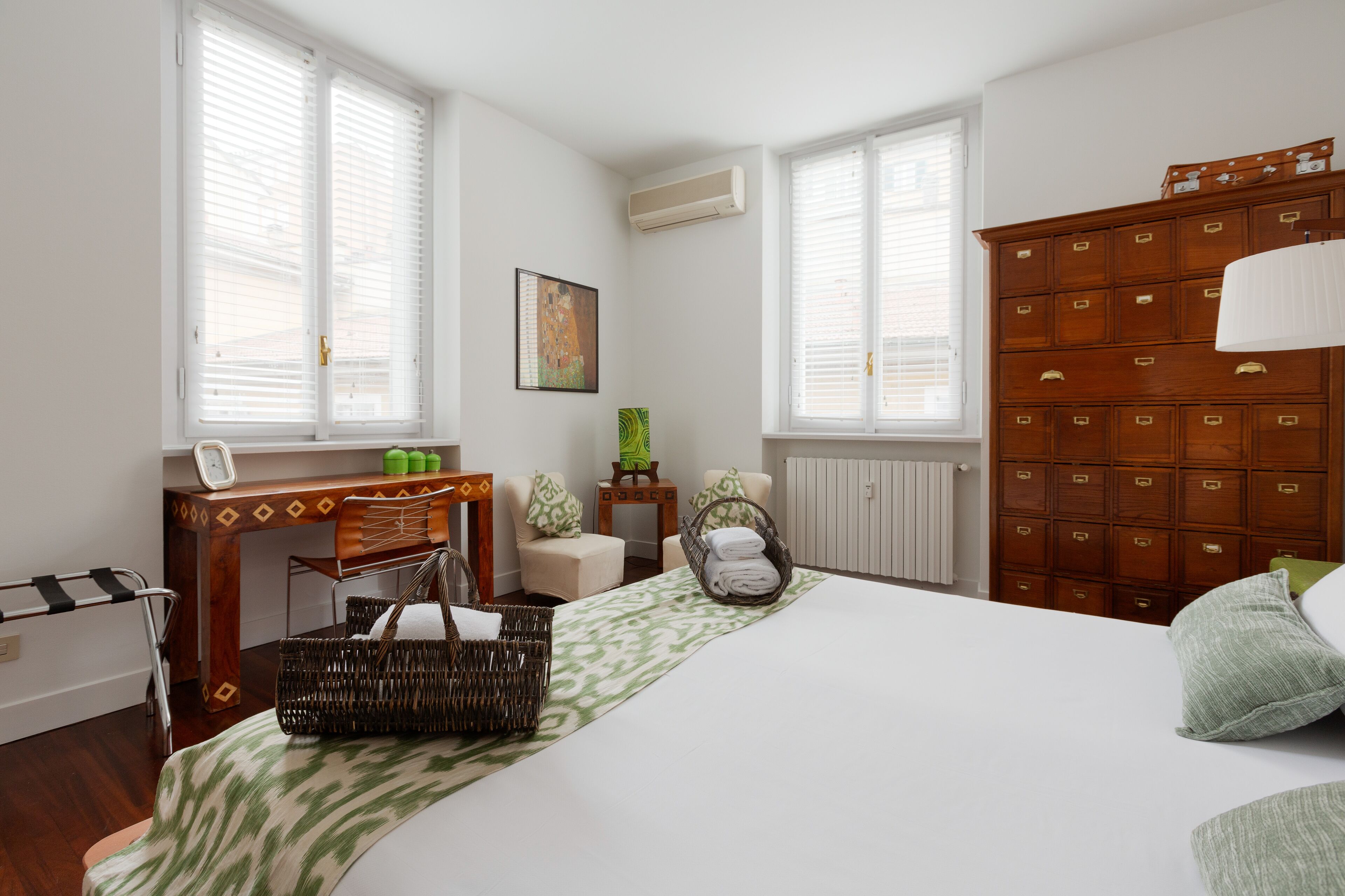 Une chambre bien rangée, avec un lit, une commode en bois, un bureau et une chaise.