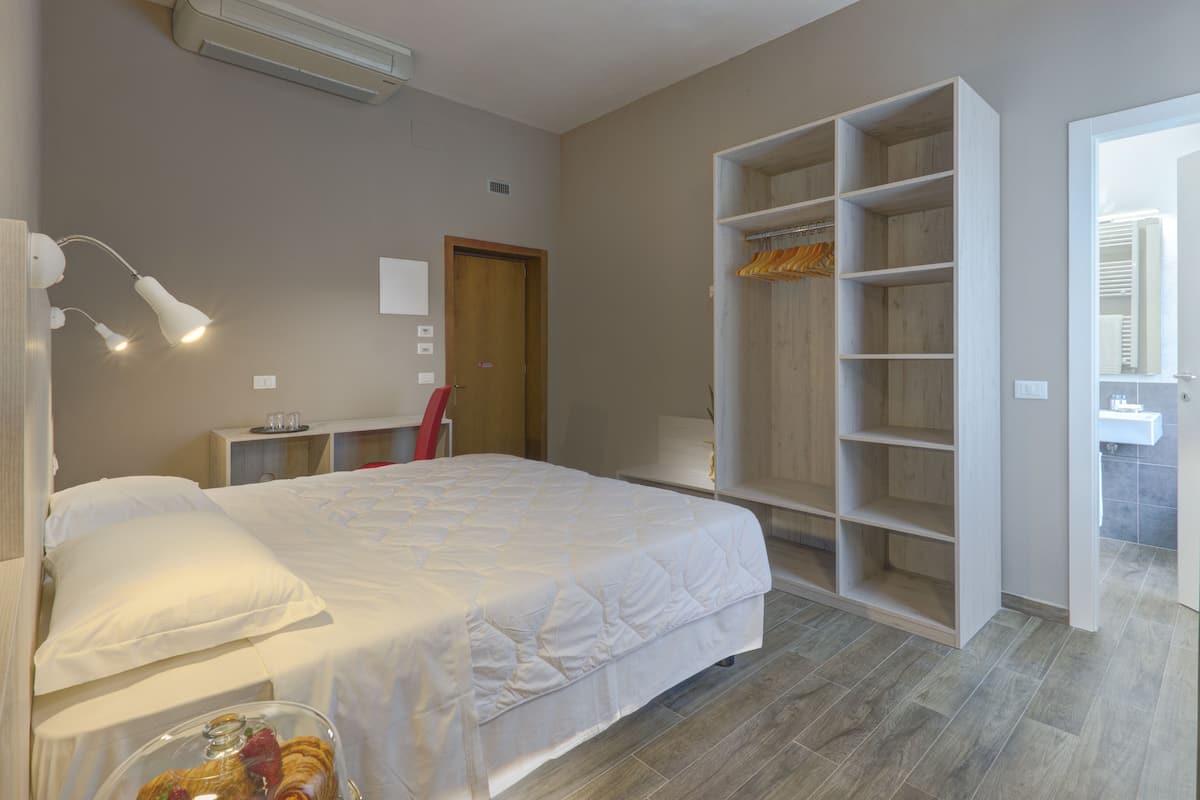 A bedroom with a bed, a wardrobe, a desk, and a mirror.