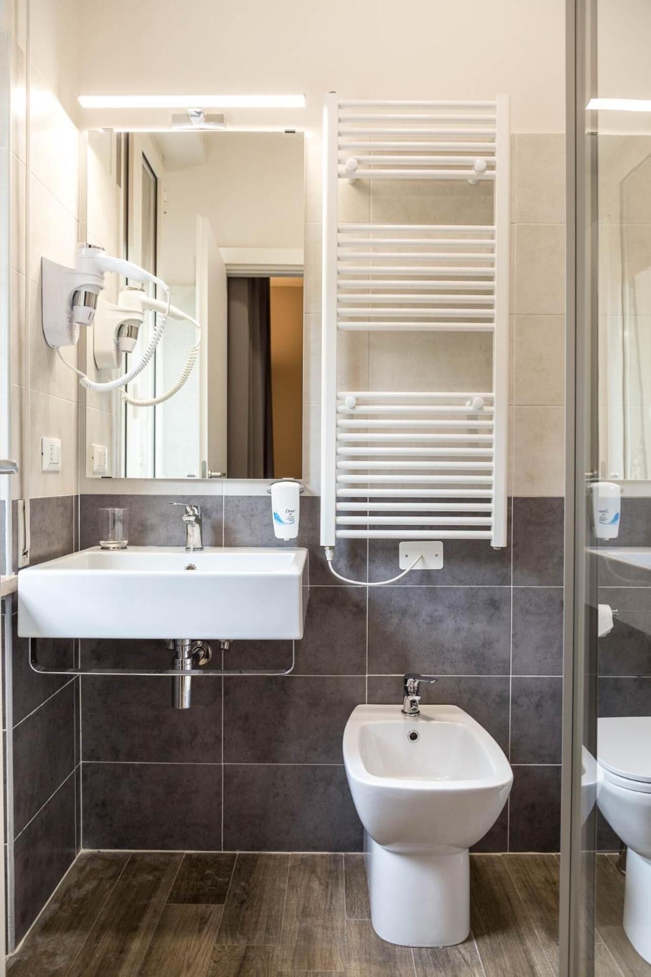A modern bathroom with a white sink, bidet, and a towel rack.