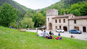 A stone building with a tiled roof, surrounded by lush greenery and hills. - Hotel Terme di Frasassi (Genga)