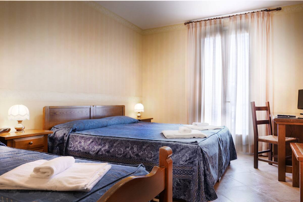 Une chambre d’hôtel avec deux lits, un bureau et une chaise.