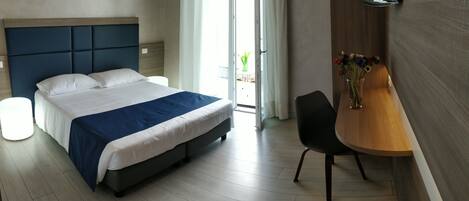 Une chambre d’hôtel moderne, dotée d’un grand lit, d’un bureau et d’une chaise.