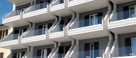 Un edificio de varios pisos con balcones, bar y mesas al aire libre.