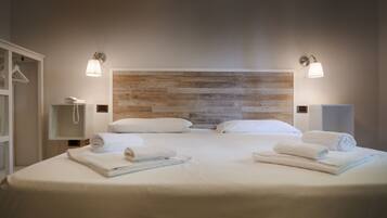 Ein Doppelbett mit weißen Bettwäsche, zwei Nachttische mit Lampen, ein Holzkopfstück und ein weißer Kleiderschrank.