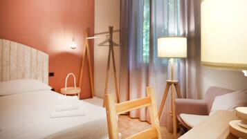 Una habitación de hotel con cama, una silla, una mesa, una lámpara y cortinas.