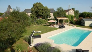 Un jardin avec une piscine, des chaises longues, une pergola et un petit abri de jardin.