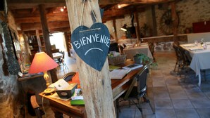 Un intérieur rustique avec une table en bois, une lampe rouge et un panneau indiquant « Bienvenue ».