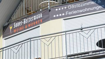 Ein Gebäude mit einem Schild, auf dem "Sauer-Kettermann WEINE & WOHNEN" und "Gästezimmer & Ferienwohnungen" steht.