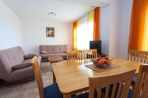 A living room with a sofa, a dining table with chairs, a TV, and a fruit bowl. - Maretsol Vacation House (Sveti Filip i Jakov)