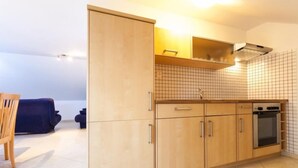 A modern kitchen with wooden cabinets, a built-in oven, and a tiled backsplash.