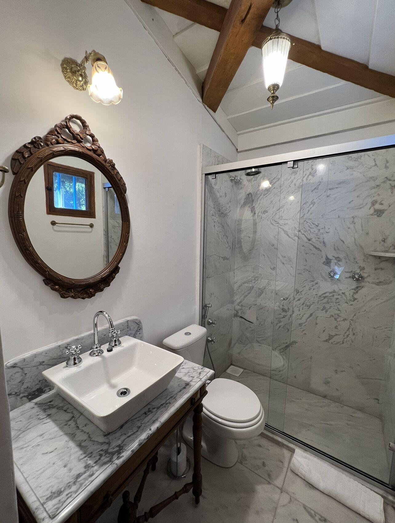 Une salle de bain avec un lavabo en marbre, des toilettes et une douche à parois de verre.