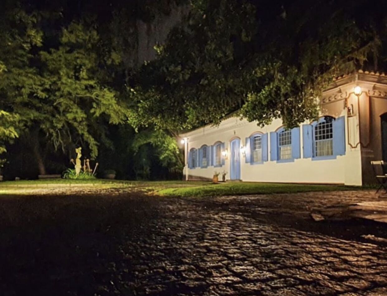 A building with a white exterior and blue accents, surrounded by trees and a cobblestone path.