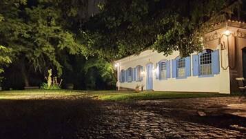 A building with a white exterior and blue accents, surrounded by trees and a cobblestone path.