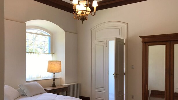 A bedroom with a bed, a lamp, a window, a door, and a wooden cabinet. - Charqueada Santa Rita Pousada de Charme (Pelotas)