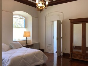 A bedroom with a bed, a lamp, a window, a door, and a wooden cabinet. - Charqueada Santa Rita Pousada de Charme (Pelotas)