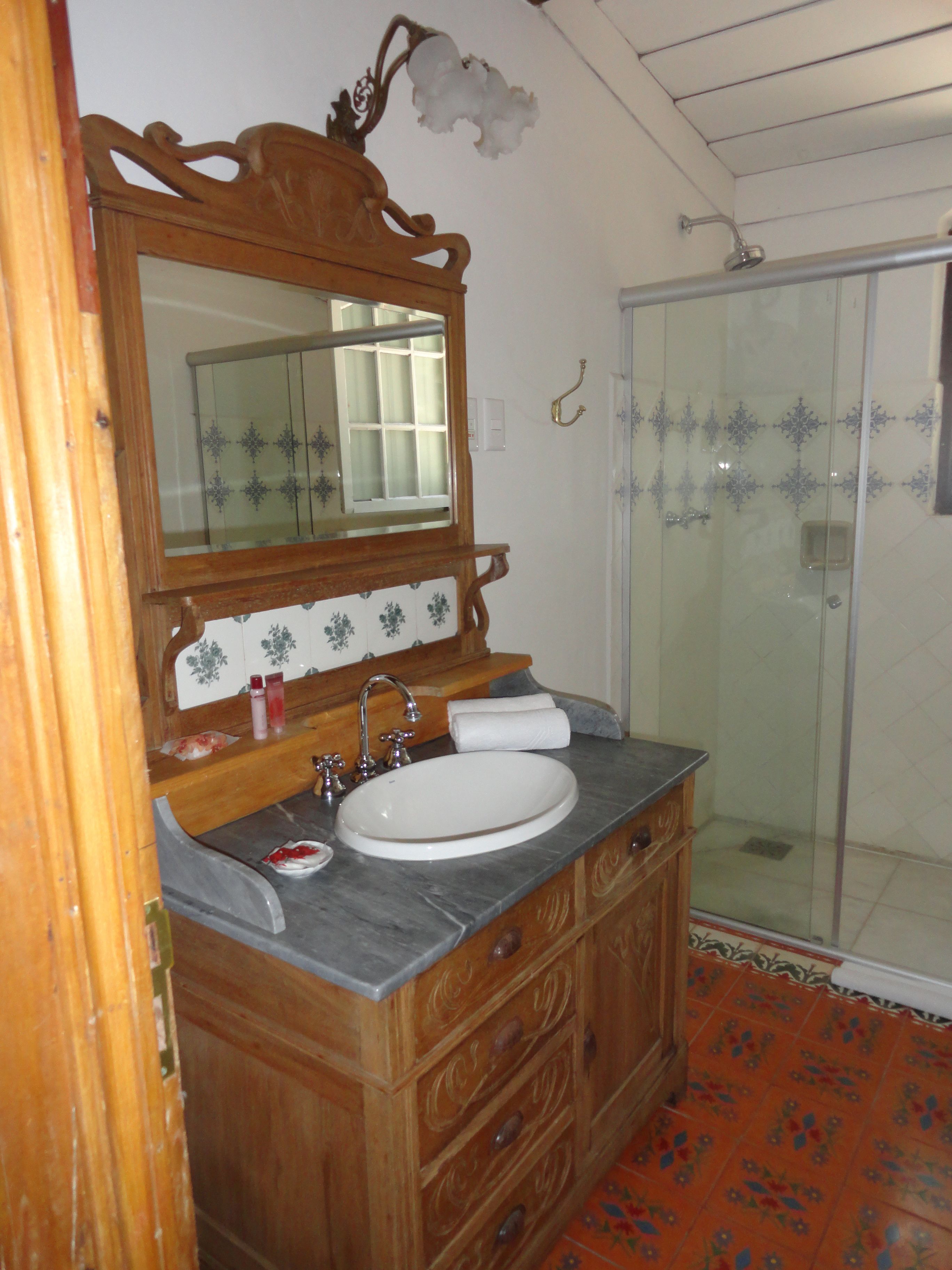 A bathroom with a wooden vanity, a large mirror, a sink, and a shower area.