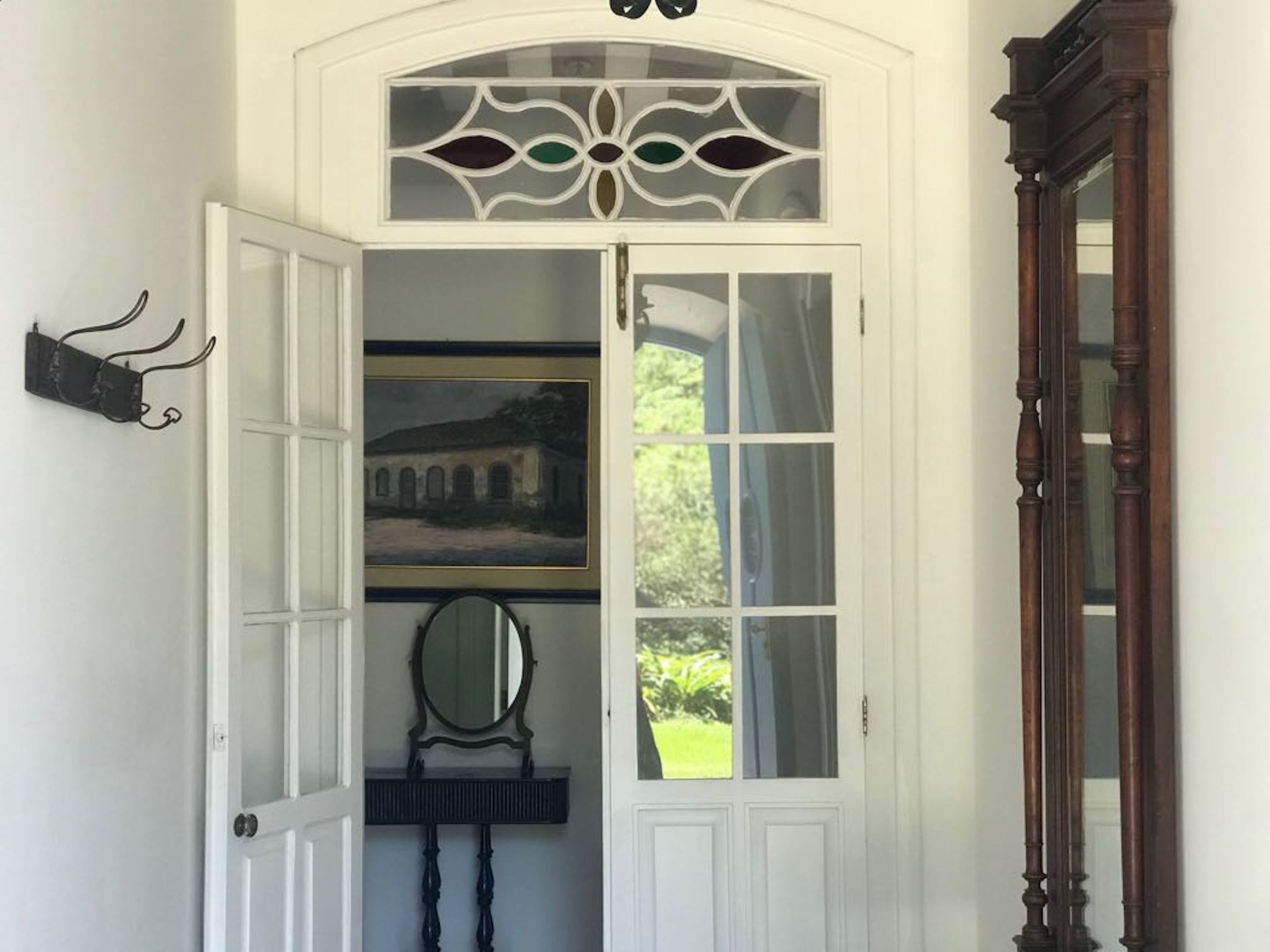 Une porte blanche avec des panneaux de verre, un tableau encadré au-dessus et un miroir en dessous.