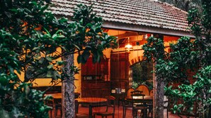An outdoor dining area with wooden tables and chairs, surrounded by greenery. - Charqueada Santa Rita Pousada de Charme (Pelotas)