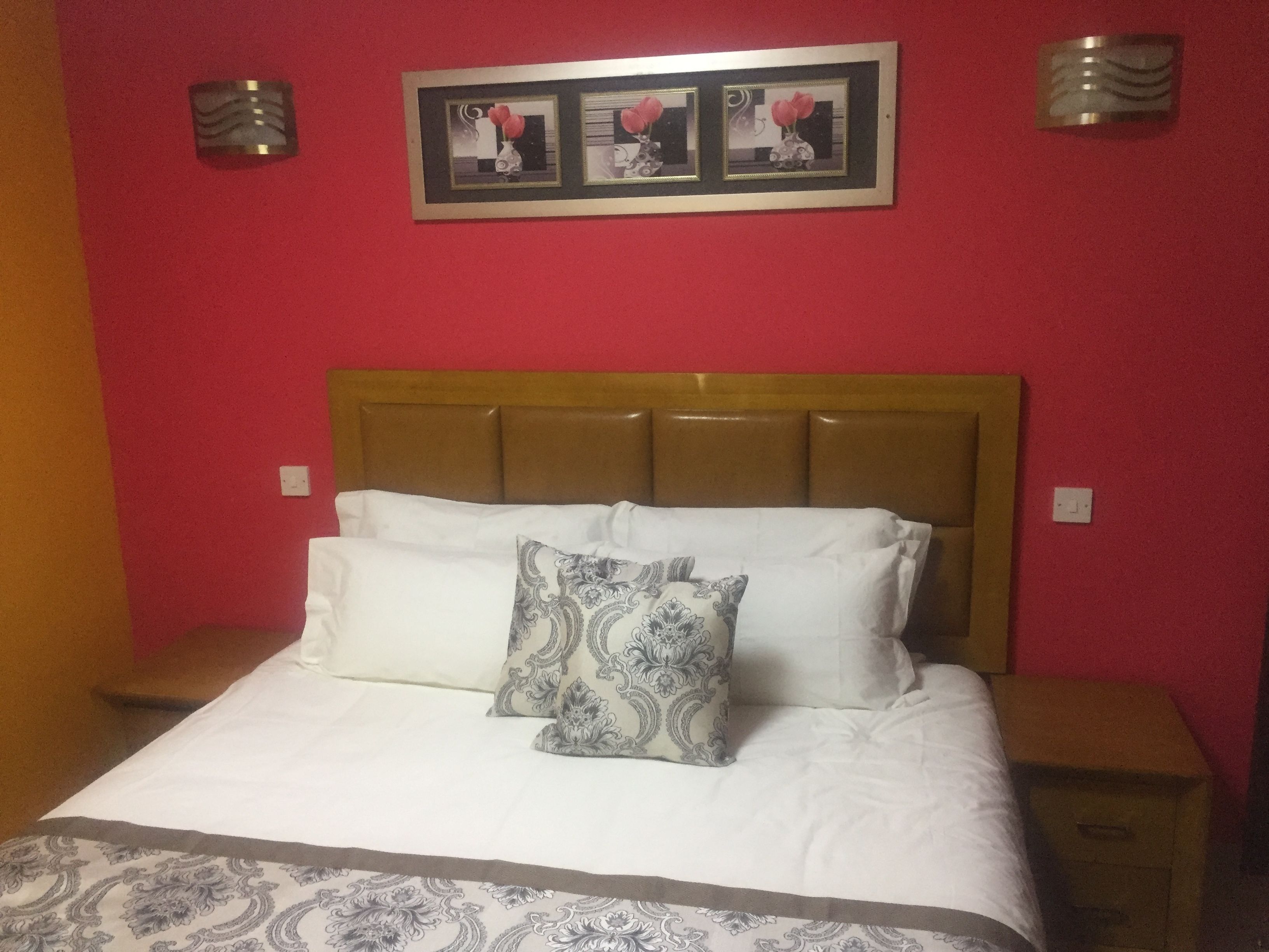 A bed with a wooden headboard, white bedding, and patterned pillows.