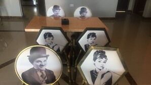 Vestíbulo de hotel con mostrador de recepción y marcos hexagonales con fotografías sobre pedestales.