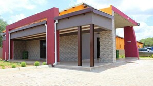 Un edificio moderno con un espacio exterior cubierto, paredes de piedra y techo plano.