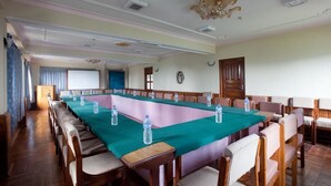 Une salle de conférence avec une longue table, des chaises et des bouteilles d’eau.
