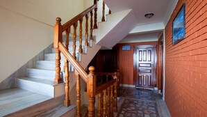 Un escalier avec des balustrades en bois menant à un palier, un sol carrelé et un mur en briques.