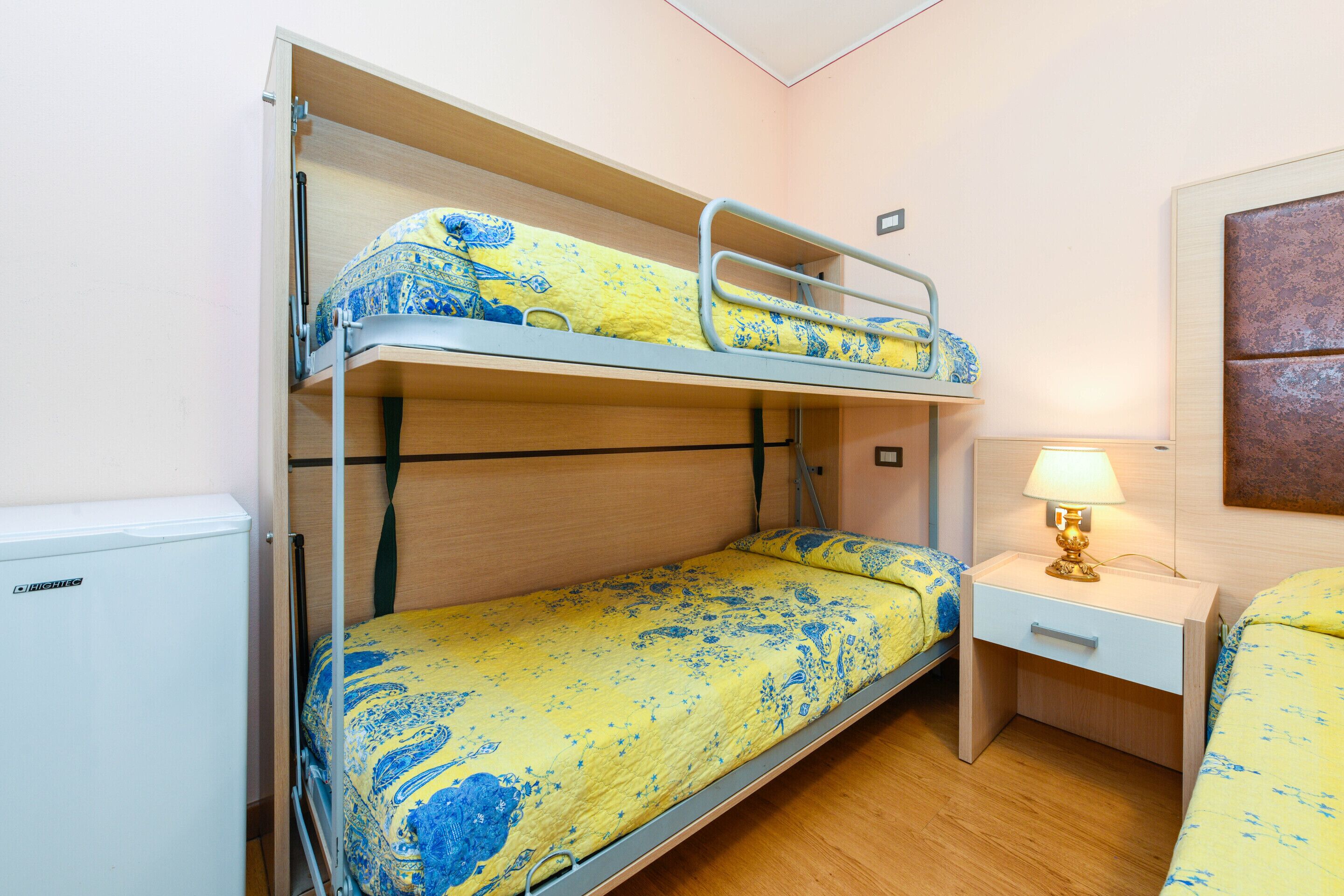 A bunk bed room with a small desk and a lamp.