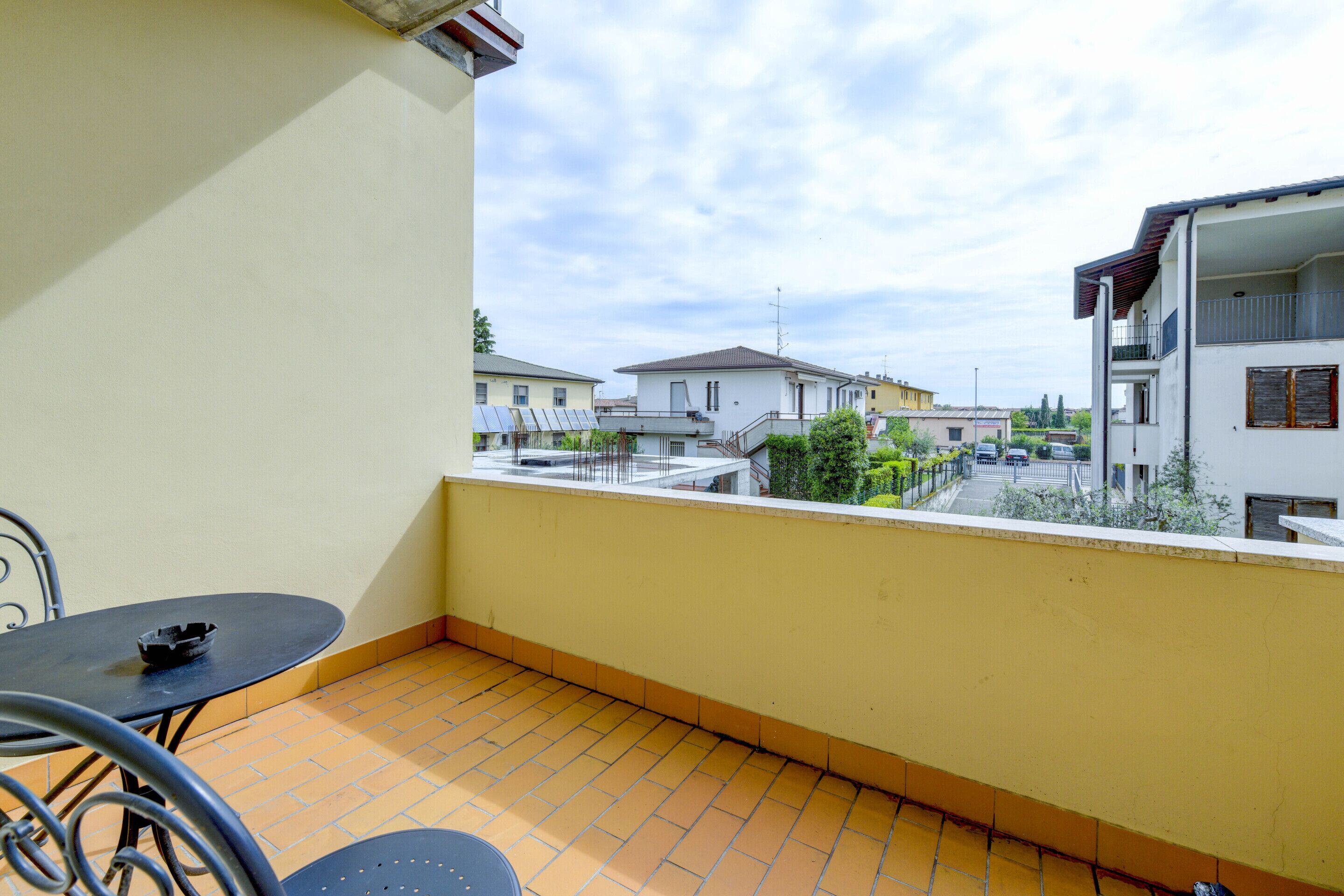 A balcony with a tiled floor, a table, and chairs.