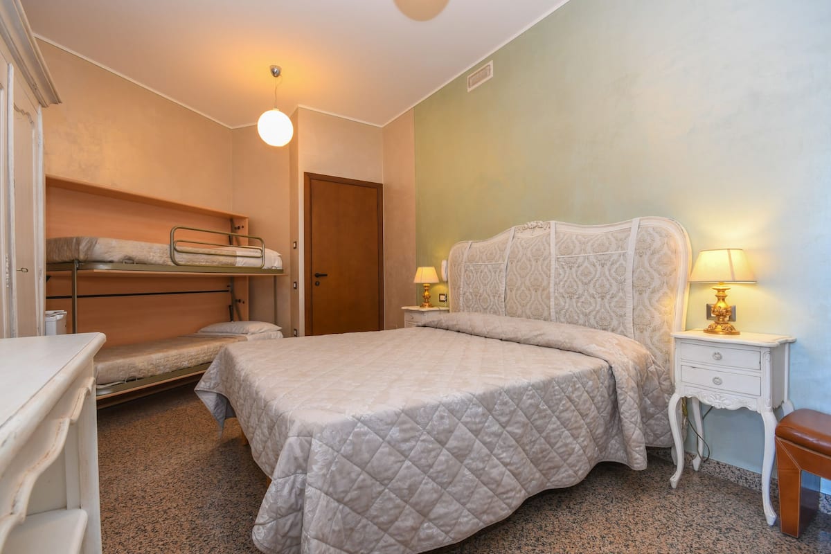 Ein Schlafzimmer mit einem großen Bett, einem kleineren Bett links, einem Nachttisch mit Lampe und einem Kleiderschrank.
